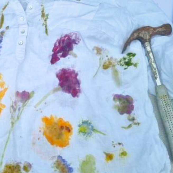 A picture of a white shirt decorated with colourful floral imprints accompanied by a hammer