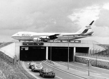 A black and white photograph of a plane on a flyover bridge