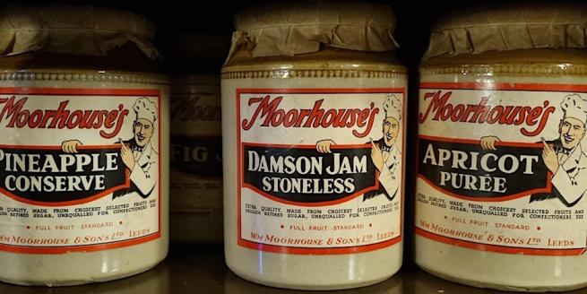 A row of three stoneware jars. Text on the labels reads 'Moorhouse's Pineapple Conserve', 'Moorhouse's Damson Jam Stoneless' and 'Moorhouse's Apricot Puree'