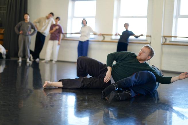 Groups go young people rolling on the floor in a dance studio with black floor