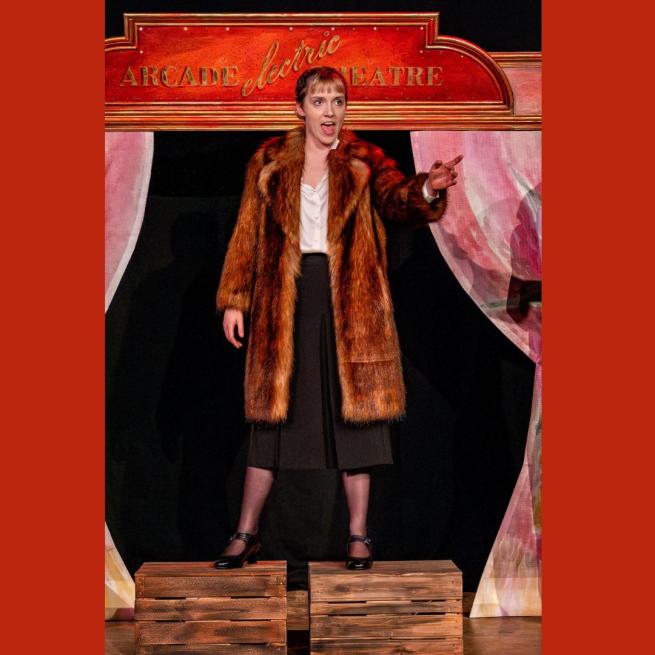 1920s woman wearing a fur coat, standing on a stage with red background