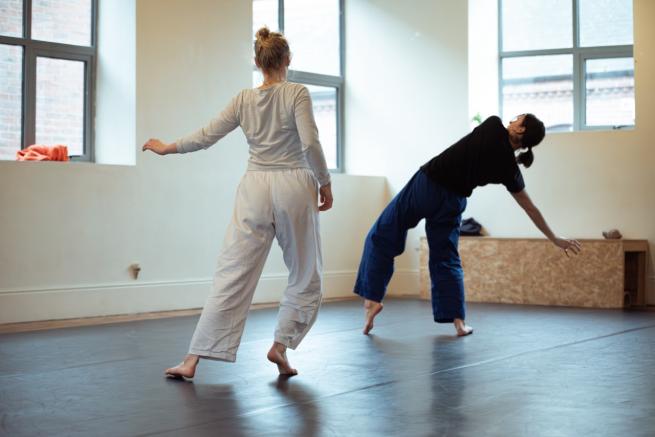 Two mid-twenty, white, females dancing in a sun lit dance studio 