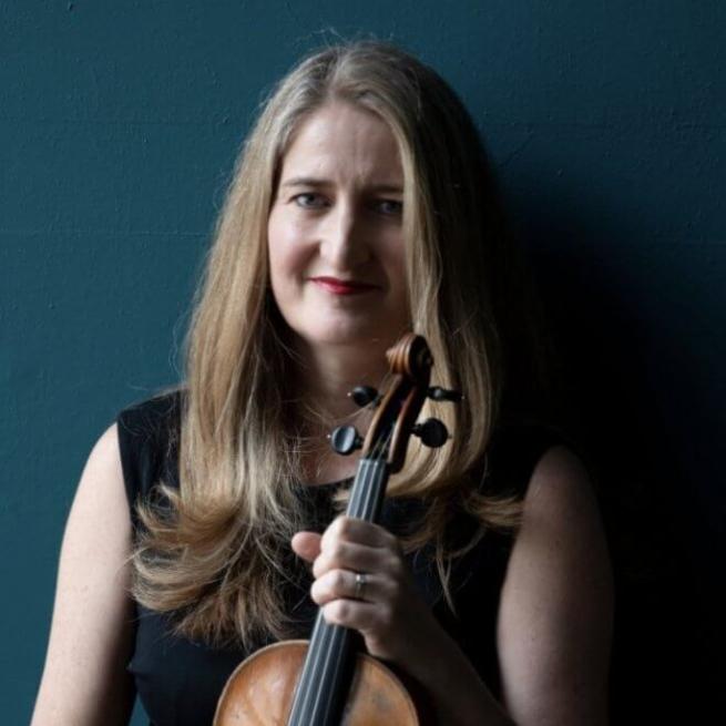 A musician holding a violin looking into the distance. 