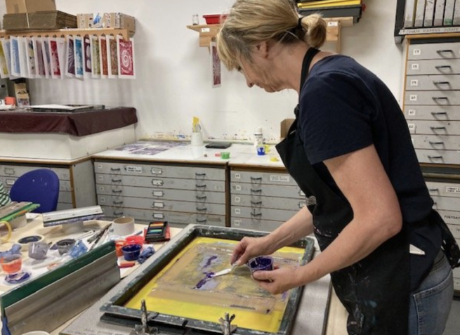 A woman preparing blue ink on a screen ready to print from