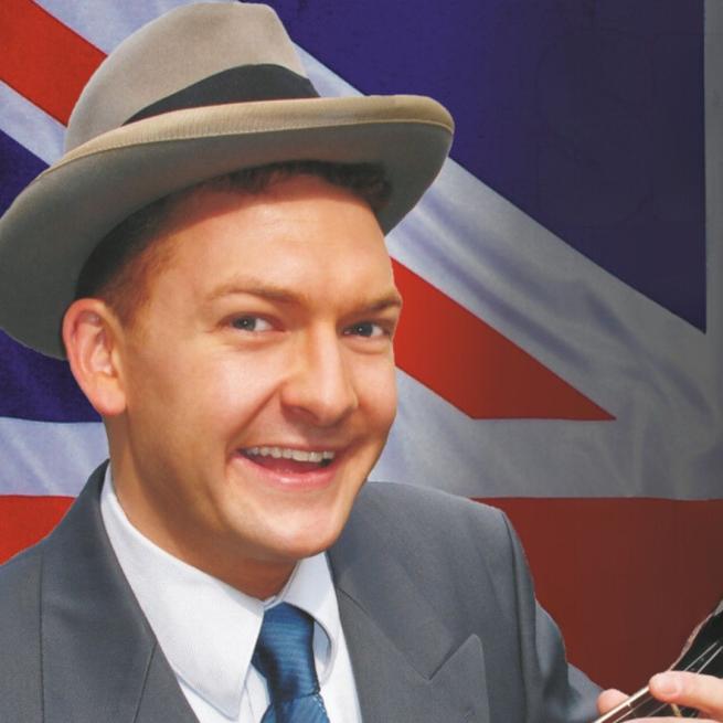 Andy Eastwood wearing a beige fedora smiling against a Union Jack background 