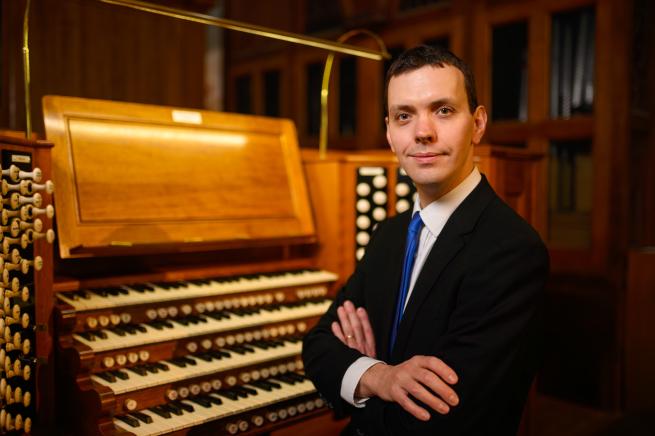 A musician sat at an organ console. 