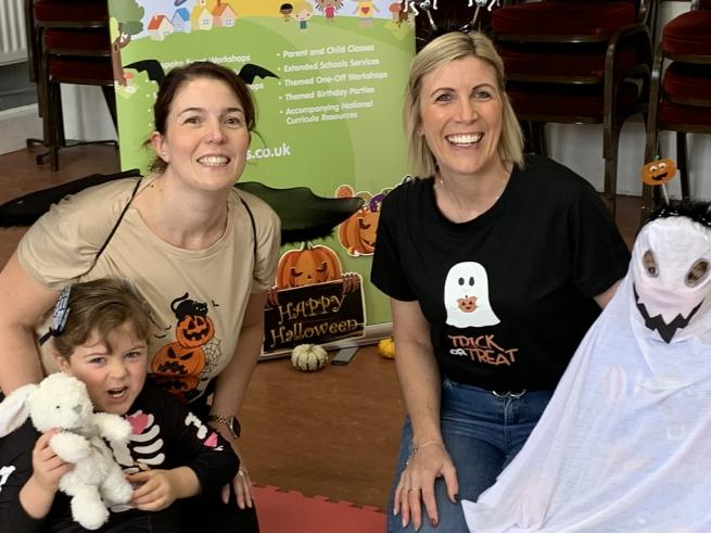 Two adults and two children in Halloween costumes. One child is holding and bunny rabbit teddy bear.