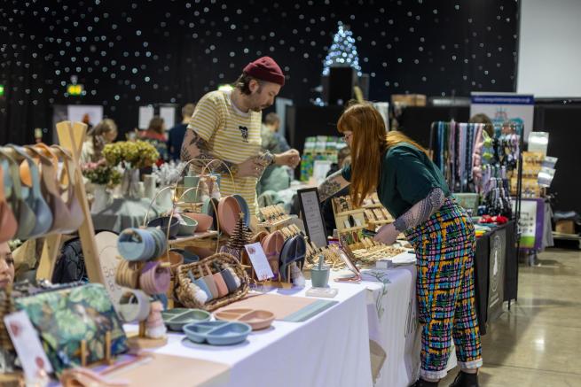 2 people setting up a craft stall at a winter flea market.