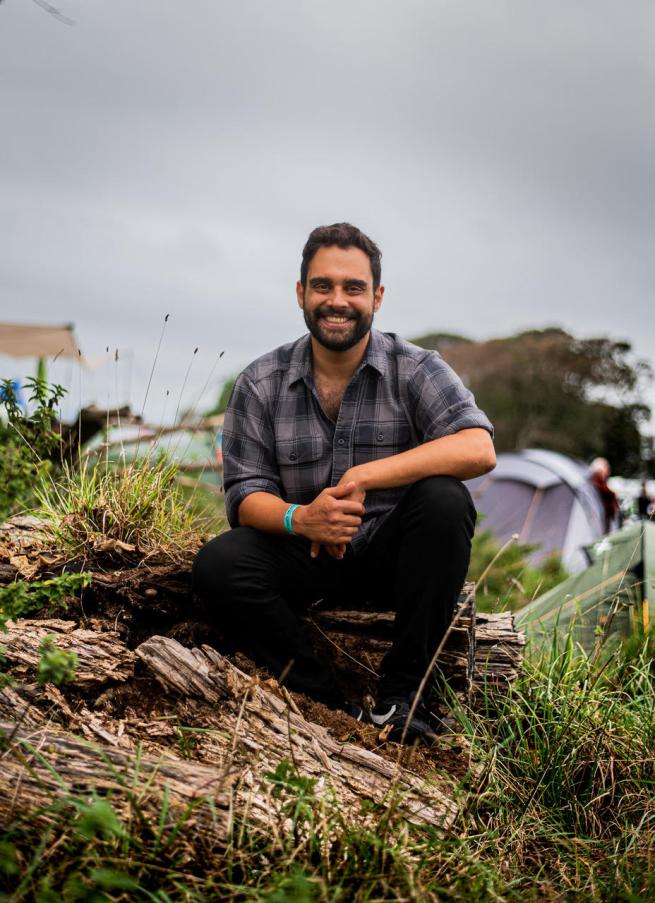 Ash Bhardwaj sitting outside on a rock 