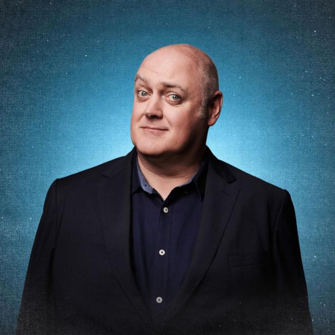 Dara Ó Briain in a black suit jacket and navy blue shirt.