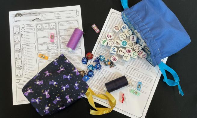 Two bags with dice on game sheets on a black background