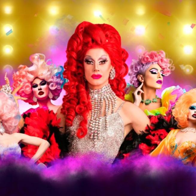 Divina De Campo with her signature red hair wearing silver surrounded by four other Drag artists and confetti.