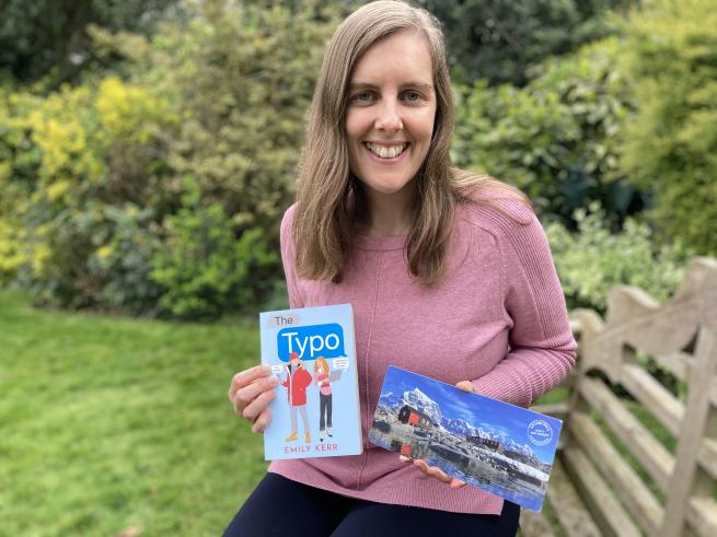 Author photo of Emily Kerr holding a copy of her book The Typo