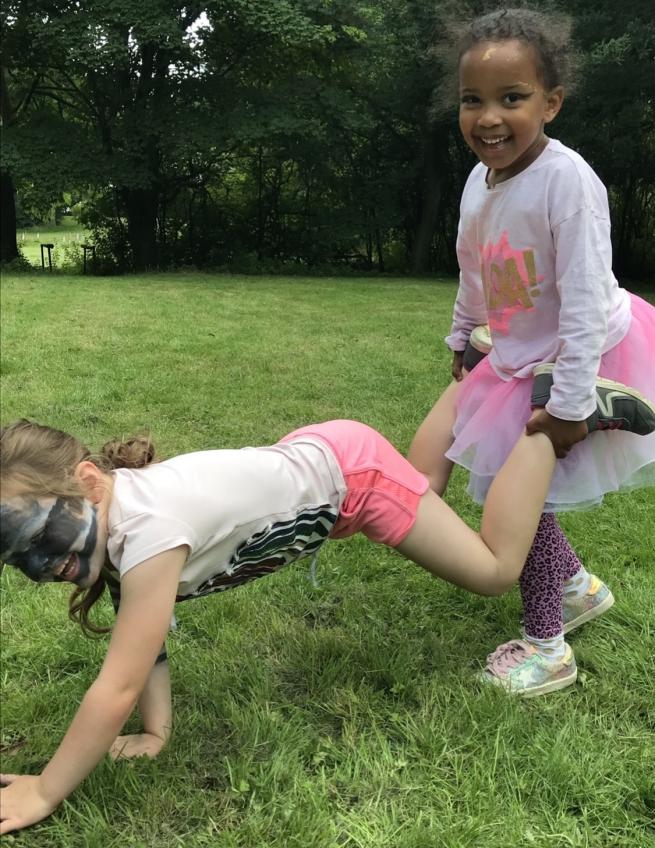 two young children doing a dance pose and smiling. One child has face paint in the style of a Zebra 