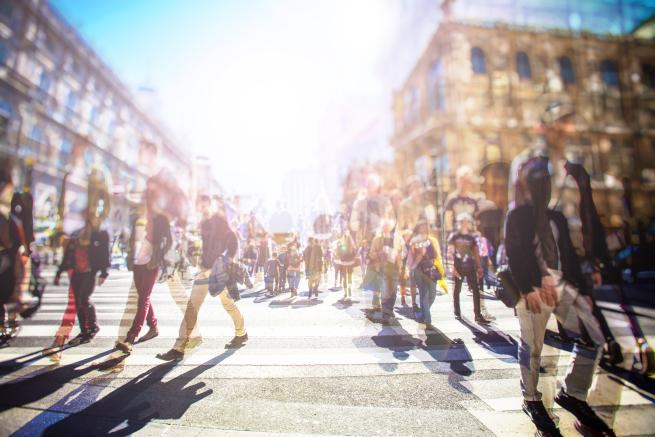 A computer generated image showing a crowd of blurred pedestrians in a daylight urban setting