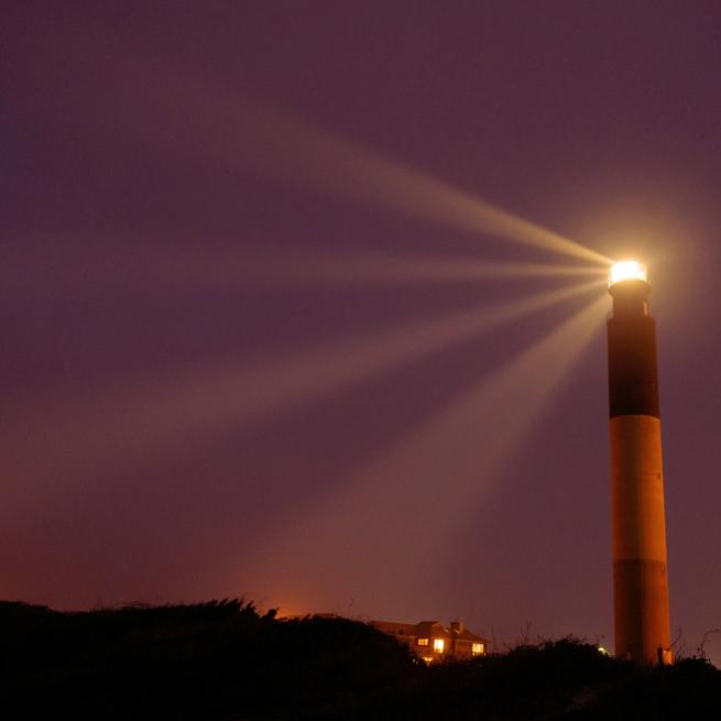 Lighthouse set amongst the landscape of a dark night sky