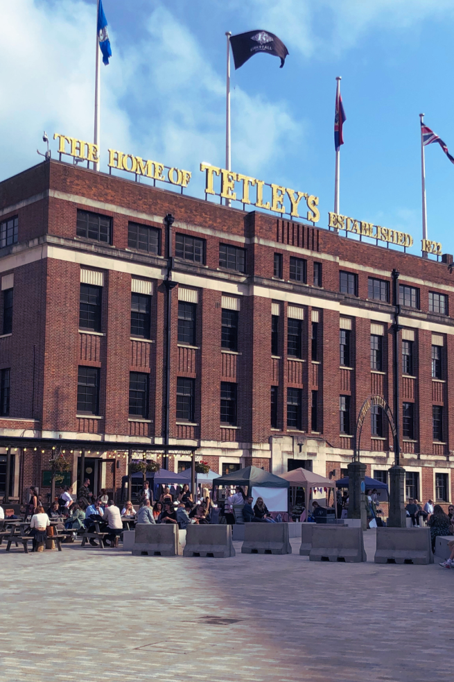 image shows the outside of The Tetley with stalls set up and lots of people sitting in the beer garden.