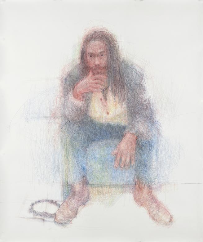 A man wearing jeans, a yellow shirt, dark open jacket and brown boots is seated on a chair. He has long hair and facial hair. He is setting thoughtfully resting his chin in his right hand. There is a necklace on the floor next to his right boot.