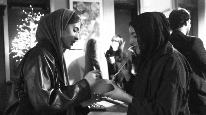 This is a black and white image of two women enjoying some food and discussing the festival