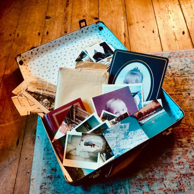 A brown open suitcase with a selection vintage childhood photographs