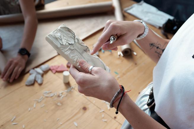 Someone using a cutting tool to cut out dear image on to a piece of lino 