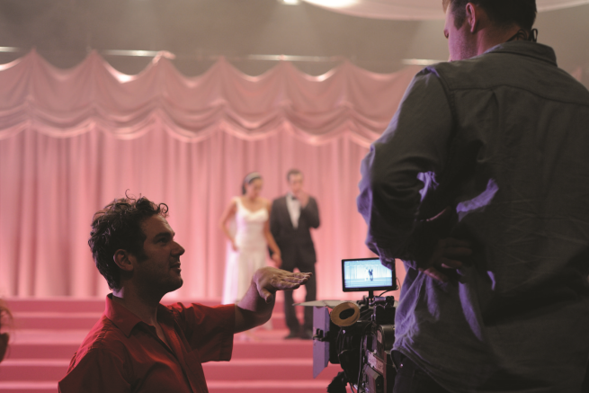 Stuart Croft pictured kneeling looking to a camera viewfinder on the set of Comma 39.