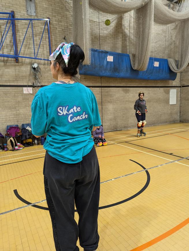 A skate coach teaches a class of roller skaters 