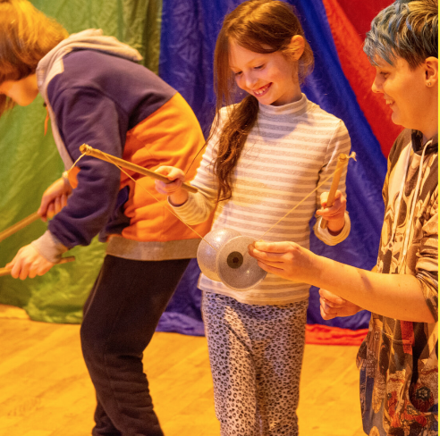 A child being shown how to use a Diablo juggling tool by a member of Circus Leeds