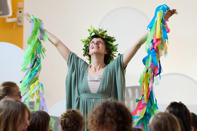 A dancer surrounded by children holds up colourful ribbons