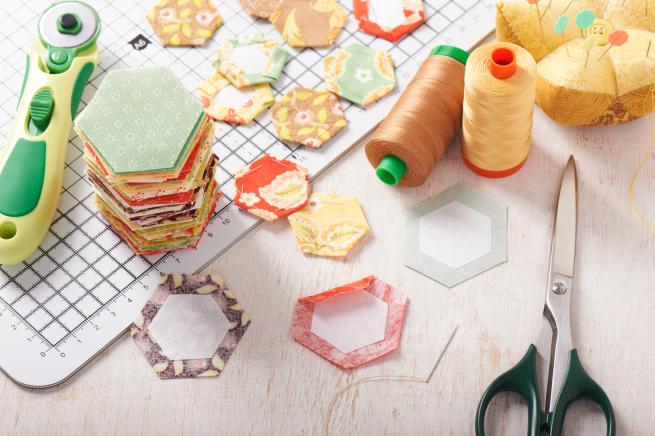 Colourful hexagons of material and cutting tools on a table top 