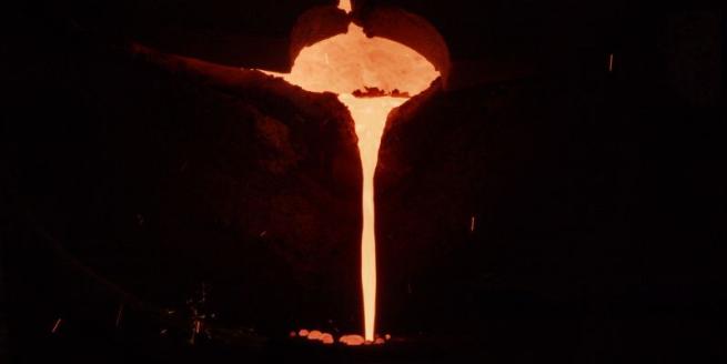 Image of molten metal pouring against a dark backdrop