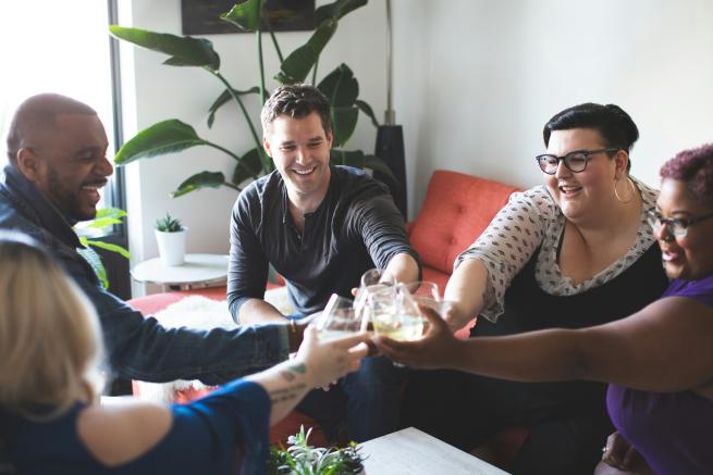 A diverse group of people clink their glasses together