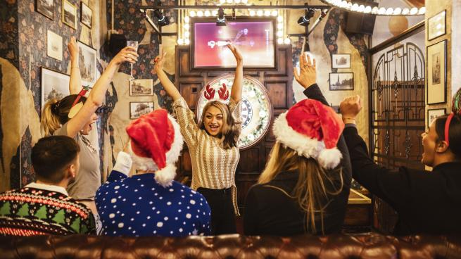 A group of people celebrating at Flight Club, with Christmas hats and jumpers on