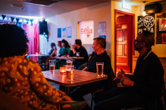 People sit at a table in a bar with full pints.