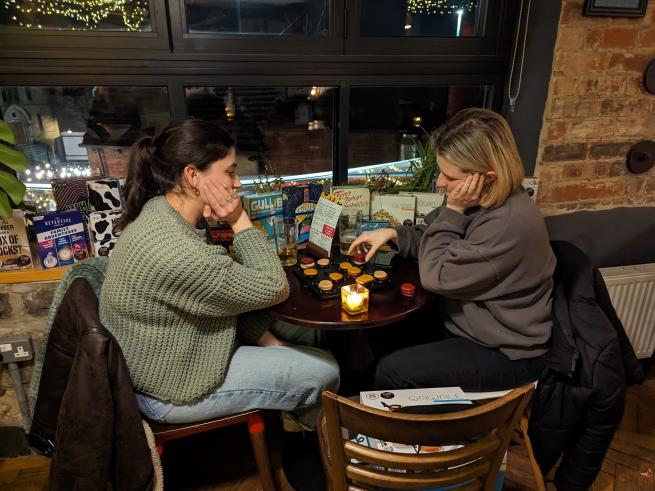 Two people are sitting playing a game. They look like they are concentrating. 