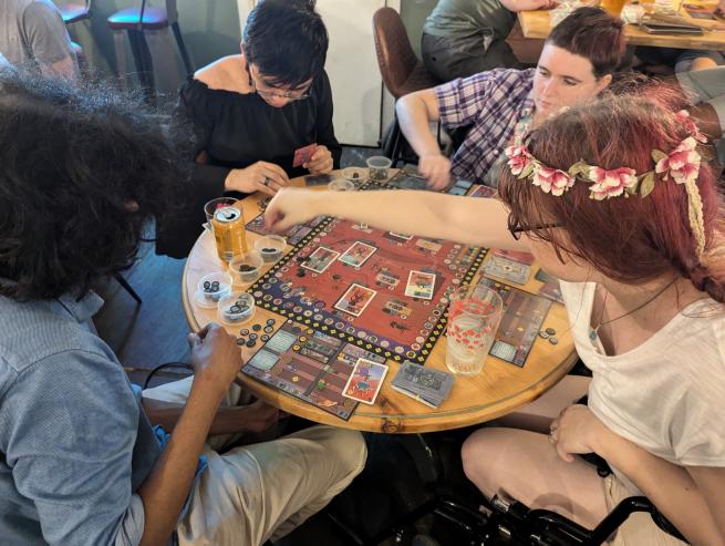 four people sitting at a table playing a boardgame