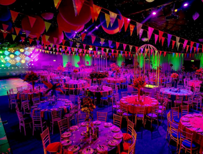 A dimly lit room of tables, decorated with colourful paper buniting 