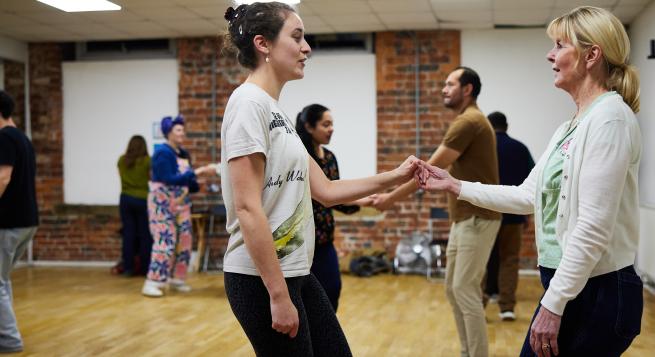 eight people of various genders, ages and races taking part in a lindy hop class