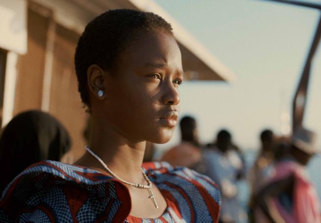 An African woman in side profile looks into the distance in a small crowd