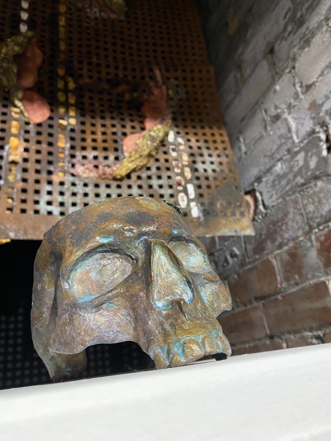 Bronze skull against a brick wall and rusted iron backdrop