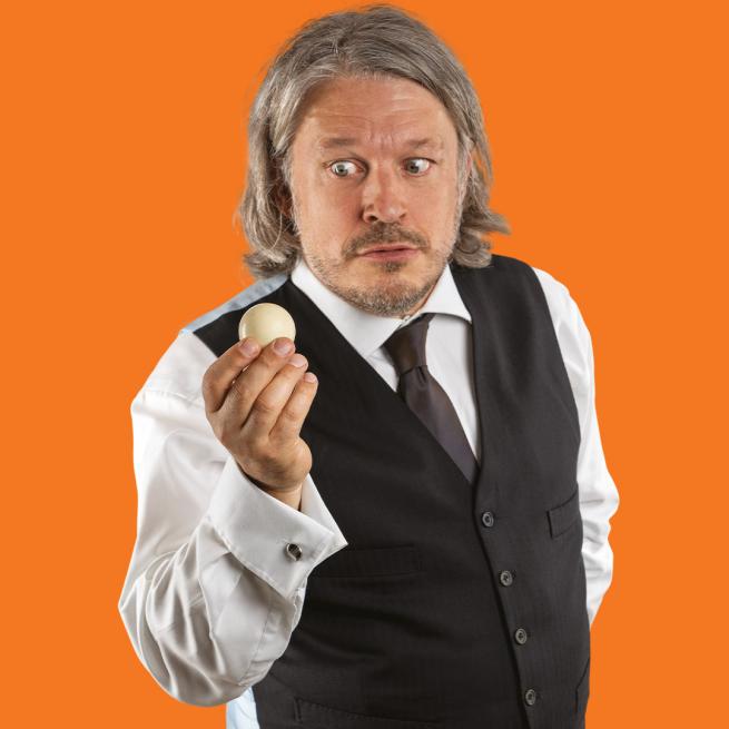 Richard Herring holding a ball against an orange background.