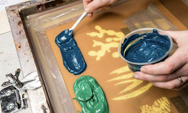 Blue and green ink being added to a screen with a plant design.