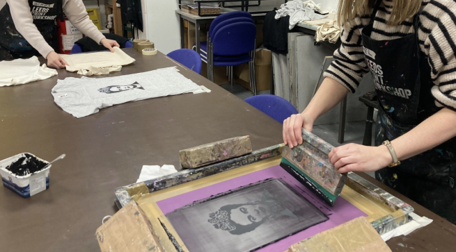 A black and white image of Frida Kahlo being screen printed onto a white t-shirt