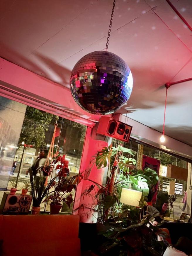 A disco ball hanging from the ceiling in a dimly lit bar.