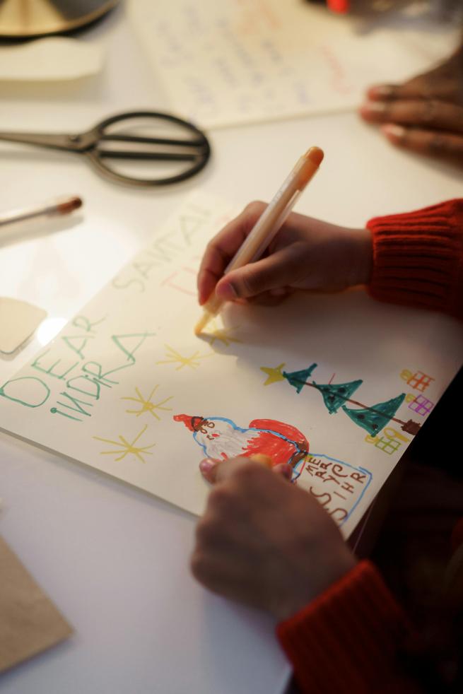 A child's hand writing a Christmas Card