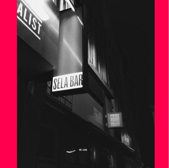 Black & White image of outdoor entrance light box - with the words Sela Bar on it.