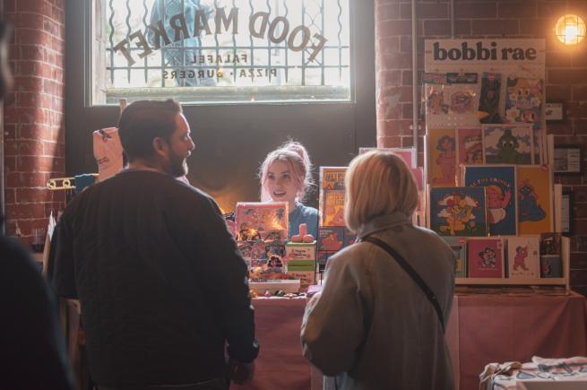 Bobbie Bearcubs Rae stands behind her stall selling prints and goodies