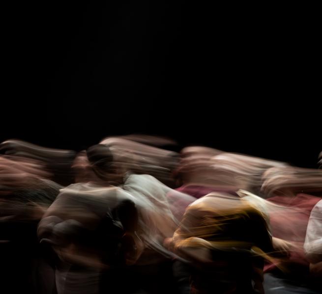 Blurred image of dancers move across a black background