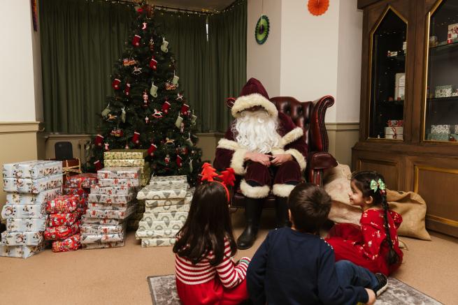 Father Christmas surrounding by presents at Temple Newsam with children in the foreground