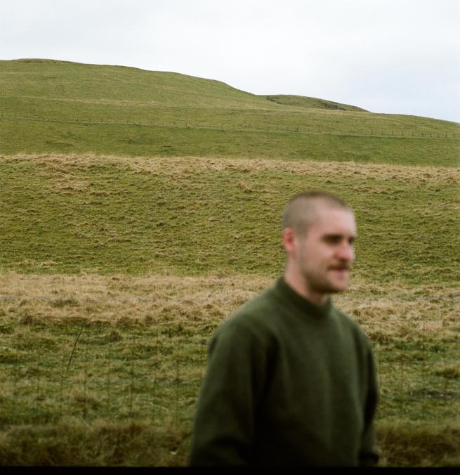 Blurred image of a male with a background of grassy hills